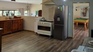 A kitchen with a wooden countertop, a stove, a refrigerator, and a dining area with a pool table. - Fat Mulberry Guest Farm (Fouriesburg)