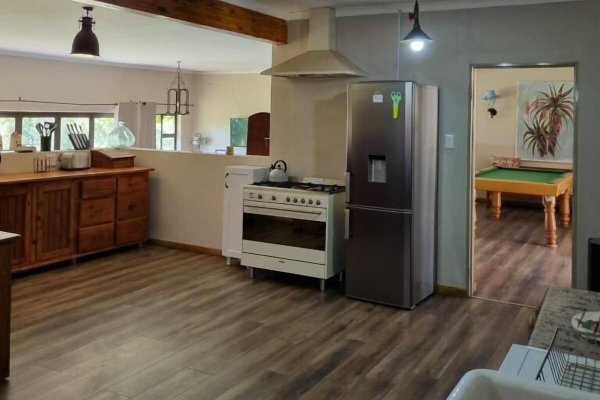 Une cuisine dotée d’un plan de travail en bois, d’une cuisinière, d’un réfrigérateur et d’un coin repas avec une table de billard.
