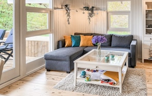 A modern living room with a sectional sofa, a glass coffee table, and a view through large windows. - 3 bedroom amazing home in Brovst (Brovst)