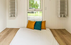 A bedroom with a bed, two pillows, a window, and a view of a car and greenery outside. - 3 bedroom amazing home in Brovst (Brovst)