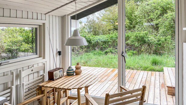 A wooden deck with a table, chairs, a radio, and a lamp.
