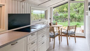 A kitchen with white cabinetry, a black stove, and a dining area with wooden furniture.