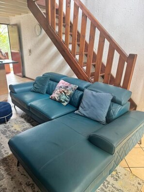A teal sofa with cushions, a wooden staircase, and a tiled floor. - Sandton 2 bed apartment (Sandton)