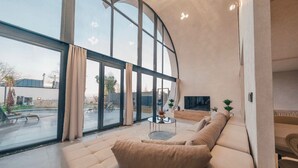 Una sala de estar moderna con un ventanal grande, un sofá, una mesa de centro y un televisor de pantalla plana.