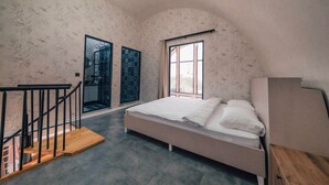 Un dormitorio con cama, escalera de madera, ventana y puerta.