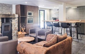 Eine moderne Küche mit Steinwand, Backofen und einer Bar mit Barhocker.