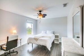 Una camera da letto con un letto, una scrivania, una sedia, una ventola a soffitto e una finestra.