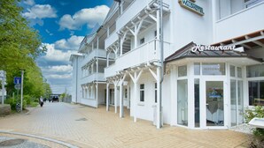 Een hotel met een restaurant op de begane grond, met een overdekte doorgang en een heldere lucht.