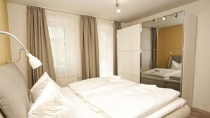 Een hotelkamer met een bed, een spiegel, een lamp en een raam met gordijnen.