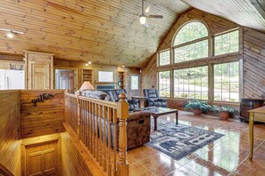 A spacious living area with a wooden interior, a fireplace, comfortable seating, and large windows offering a view of the outdoors. - Family Smoky Mountain Retreat! 5BR House (Sevierville)