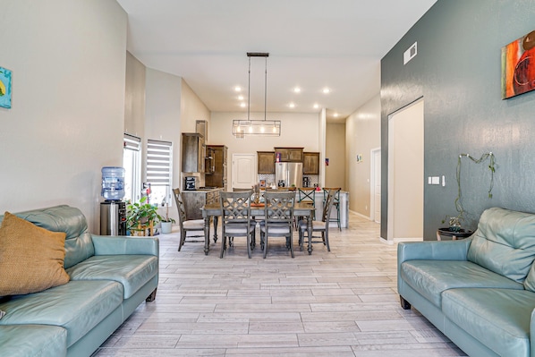A modern living room with a dining area, a water dispenser, and a refrigerator.