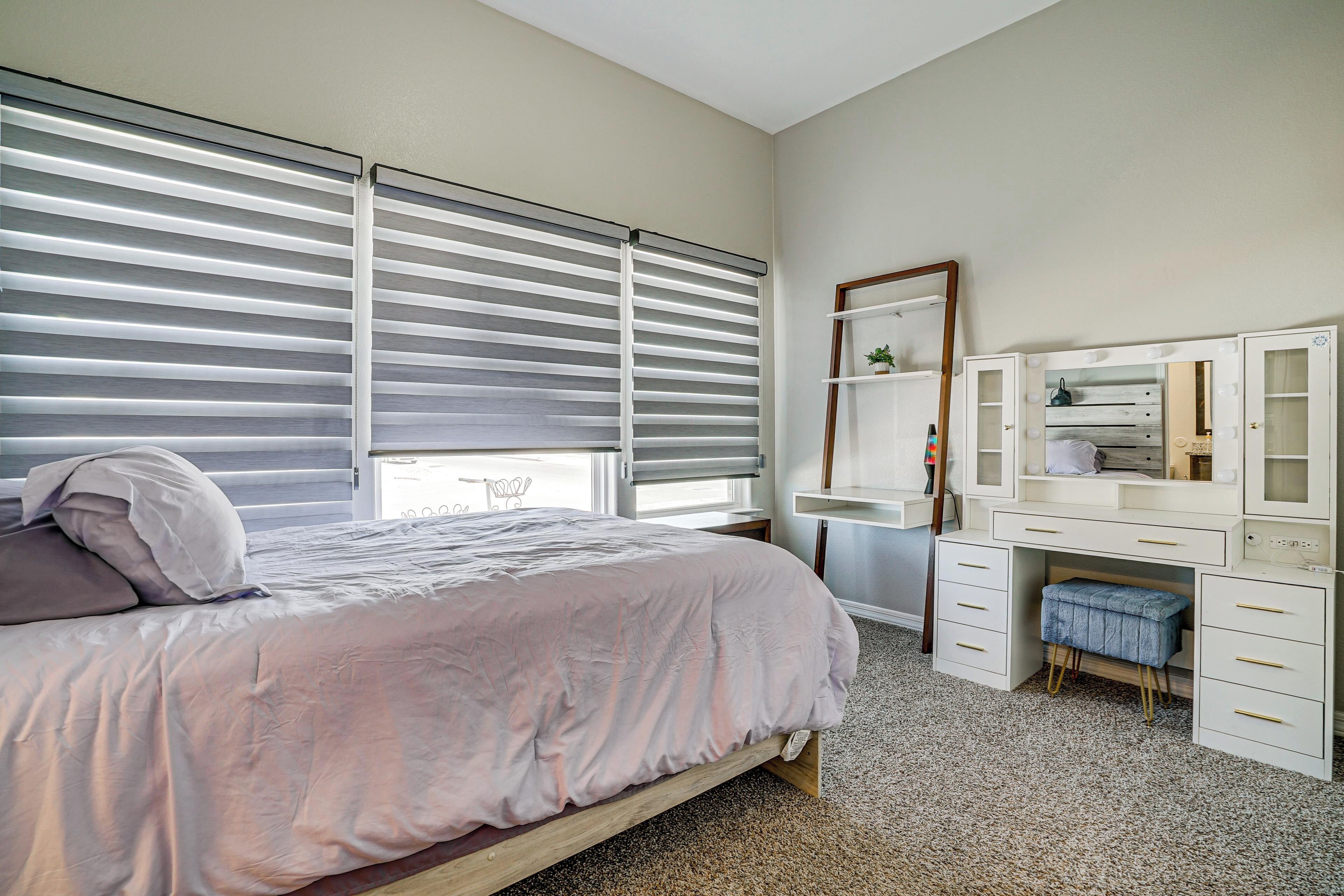 Une chambre à coucher avec un lit, une coiffeuse avec un miroir et un bureau.