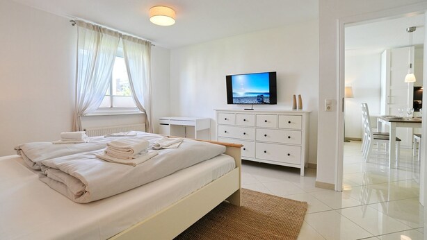 Ett hotellrum med en säng, en TV, en byrå och en matplats.