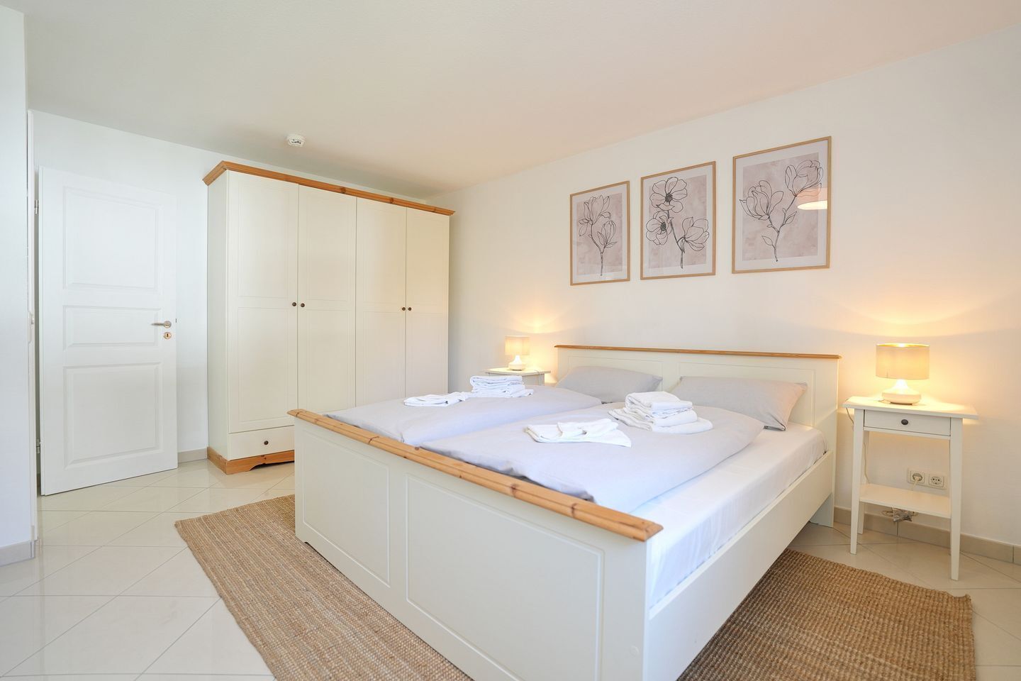 A bedroom with a bed, bedside tables, a wardrobe, and wall art.