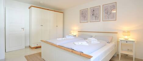 A bedroom with a bed, bedside tables, a wardrobe, and wall art.