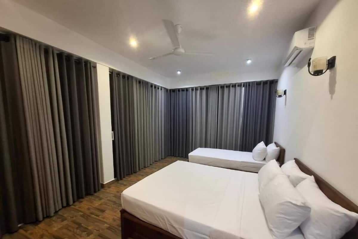 A hotel room with a large bed, a smaller bed, a ceiling fan, and an air conditioning unit.