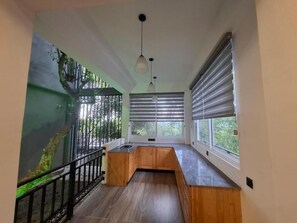 Cocina moderna con un banco de madera, un lavamanos y vistas a través de una ventana con persianas.