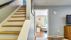 A staircase leading to a living area with a television, a clock, and a power outlet on the wall. - Private Hot Tub, Yard & Games Galore: Plymouth Gem (Plymouth)