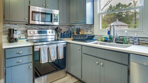A kitchen with grey cabinets, stainless steel appliances, and a window with a view of a house. - Private Hot Tub, Yard & Games Galore: Plymouth Gem (Plymouth)