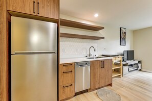 Eine moderne Küche mit Edelstahlkühlschrank, Holzschränken, Geschirrspüler und integriertem Backofen.