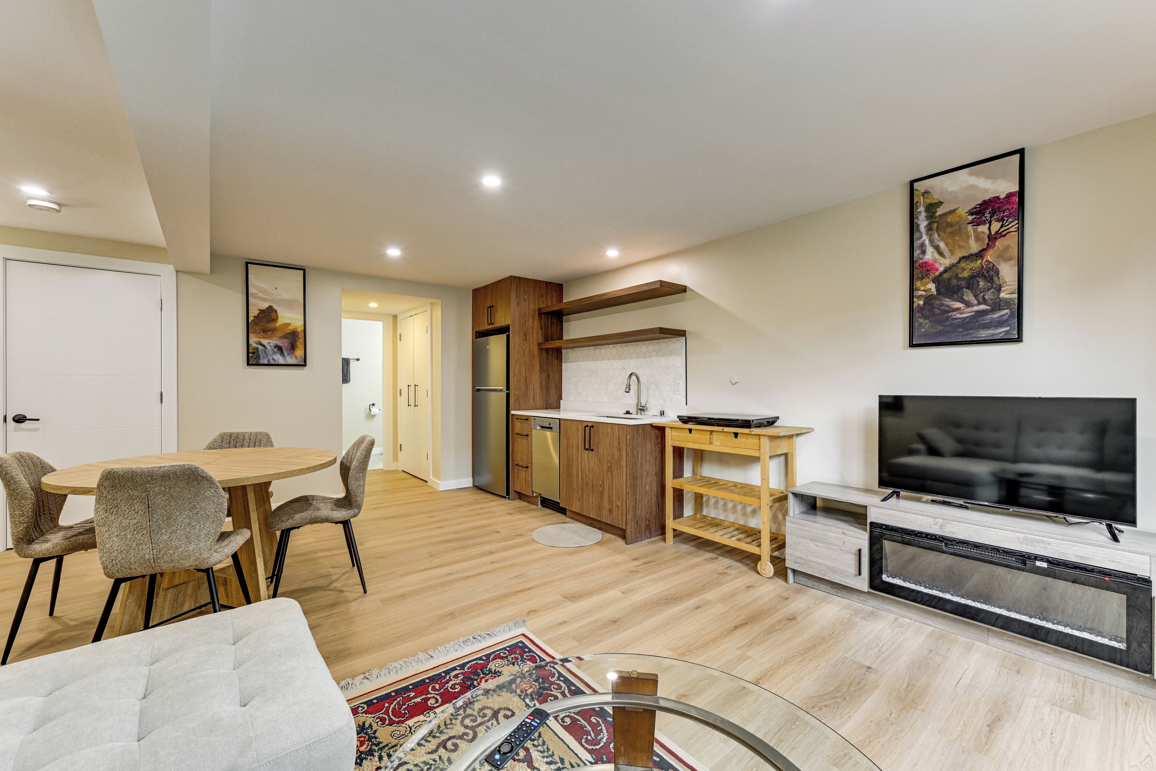 A modern living space with a dining area, kitchen, and entertainment unit.