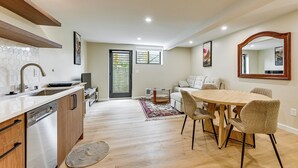 A modern kitchen with a dishwasher, wooden cabinets, and a large window. - Walk to Seward Park! Pet-Friendly Apt w/ Turf Yard (Seattle)
