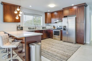 Una cocina moderna con armarios de madera, electrodomésticos de acero inoxidable, una barra y un ventanal grande.