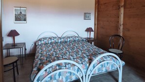Ein Schlafzimmer mit einem Bett, zwei Stühlen, einem Tisch und einer Lampe.