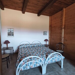 A bedroom with a bed, two chairs, a table, and a lamp.