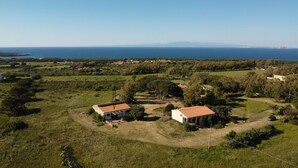 Ein ländliches Anwesen mit zwei Häusern, freiem Blick auf das Meer und einer hügeligen Landschaft.