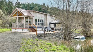 Une cabane avec un porche, un espace extérieur aménagé et couvert, et un quai au bord d’un lac.