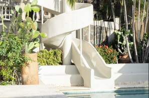 Eine Wendeltreppe neben einem Pool, umgeben von Topfpflanzen und einer Steinmauer.
