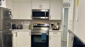 A modern kitchen with stainless steel appliances, white cabinetry, and a tiled backsplash. - Cozy Private Suite Near Stoney & Deerfoot Trails (Calgary)