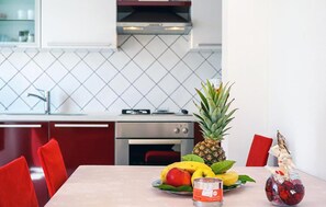 Una cucina moderna con un tavolo da pranzo apparecchiato per due, con un vassoio di frutta, una candela e un bicchiere di vino rosso.