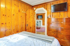 Een slaapkamer met houten wanden, een bed, een televisie en een kledingkast.
