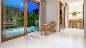 Ett modernt rum med en glasdörr som leder ut till en pool, ett litet runt bord med en stol och ett skrivbord med en stol.