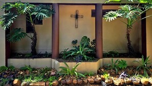 Un jardín con una cruz, plantas y un sendero de piedra.