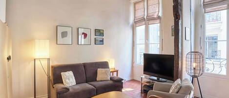 A living room with a sofa, a TV, a lamp, and a window with a view.