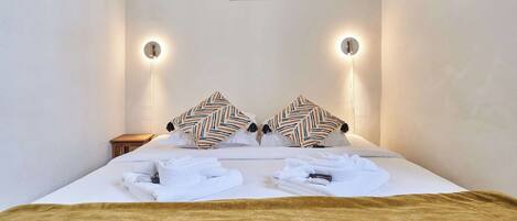 Ein Hotelzimmer mit einem Bett, zwei Wandleuchten, einem gerahmten Bild und einem kleinen Nachttisch.