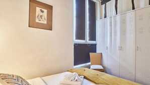 Een slaapkamer met een bed, een raam, een stoel en een aantal kasten.