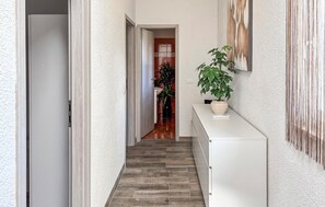 Ein Flur mit einem weißen Schrank, einer Topfpflanze und einer Tür zu einem Badezimmer.