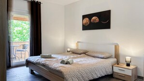 Quarto com cama, mesas de cabeceira, uma obra de arte na parede e vista pela janela.