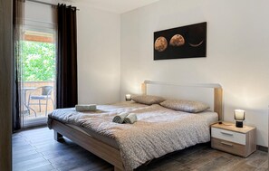 Ein Schlafzimmer mit Bett, Nachttischen, einem Wandbild und Blick durch ein Fenster.