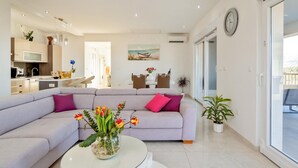 A modern living room with a sofa, a glass coffee table, and a dining area in the background. - Stunning home in Lumbarda (Lumbarda)