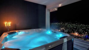 A hot tub with a candelabra, surrounded by a dark wall and a view of a lit garden at night. - Stunning home in Lumbarda (Lumbarda)