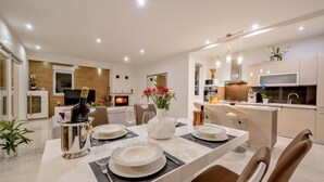 A modern dining area with a table set for four, a fireplace, and a kitchen in the background. - Stunning home in Lumbarda (Lumbarda)
