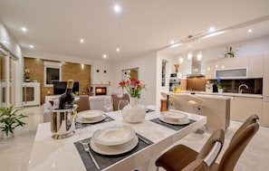 A modern dining area with a table set for four, a fireplace, and a kitchen in the background. - Stunning home in Lumbarda (Lumbarda)