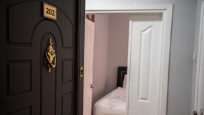 A dark wooden door with a brass handle and a number plate reading '202'.