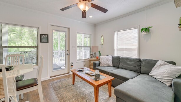 A living room with a ceiling fan, a gray sofa, a wooden coffee table, and a dining area with a white chair and table. - Pool & Lake Access! Sherrills Ford Tiny Home (Sherrills Ford)