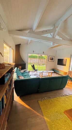 Ein geräumiges Wohnzimmer mit einem großen, grünen Ecksofa, einem Holztisch und einem gelben Teppich.
